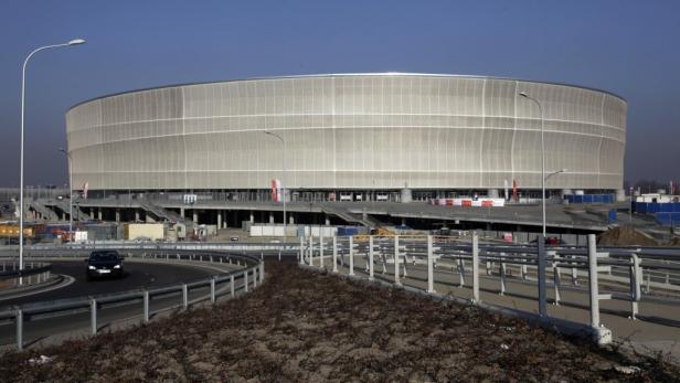 Das runde Äußere eines Stadions mit Parkplätzen und Straßen davor.