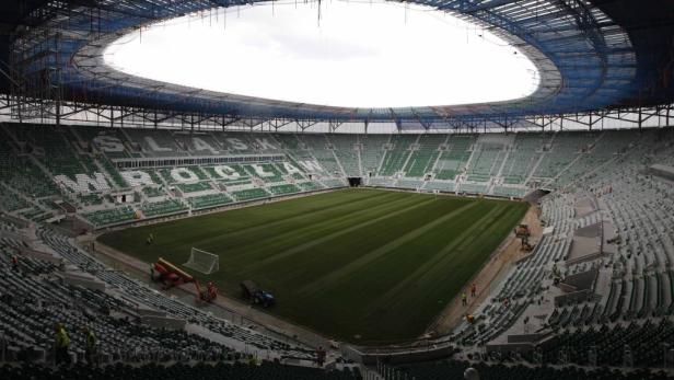 Das Stadion Wrocław mit grünen Sitzen und einem Rasenfeld.