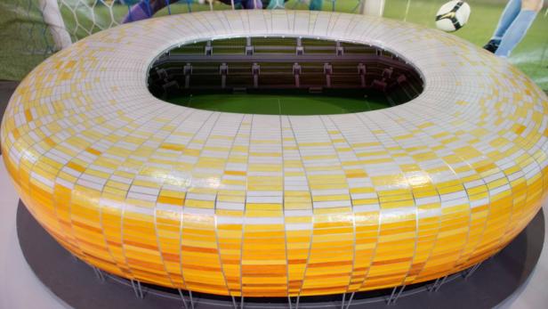 Ein Modell eines Fußballstadions mit gelb-weißer Fassade.