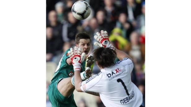 Ein Fußballspieler versucht, den Ball am Torwart vorbeizuschießen.