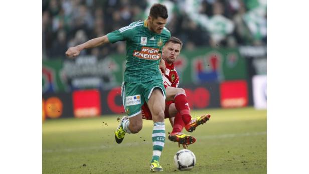 Zwei Fußballspieler kämpfen um den Ball auf dem Spielfeld.