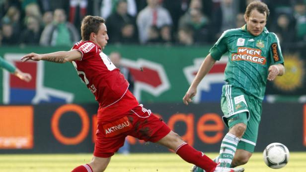 Zwei Fußballspieler kämpfen um den Ball während eines Spiels.