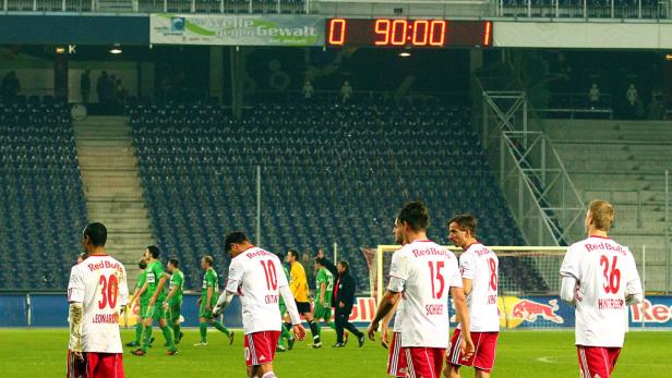 Fußballspieler verlassen nach dem Spiel das Feld; die Anzeigetafel zeigt 0:1 in der 90. Minute.