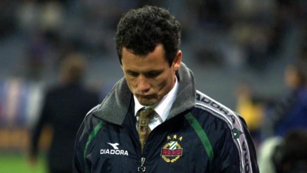 Ein Mann in einer Jacke des SK Rapid Wien blickt nach unten.