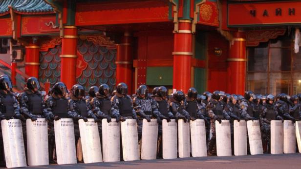 Eine Reihe von Polizisten in Schutzausrüstung steht vor einem Gebäude im chinesischen Stil.