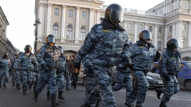 Eine Reihe von OMON-Polizisten in Kampfmontur marschiert eine Straße entlang.