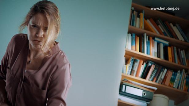 Eine Frau in einem Morgenmantel schaut mit zusammengezogenem Gesicht nach unten.