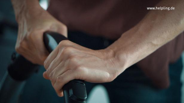 Eine Person hält das Rohr eines Staubsaugers fest.