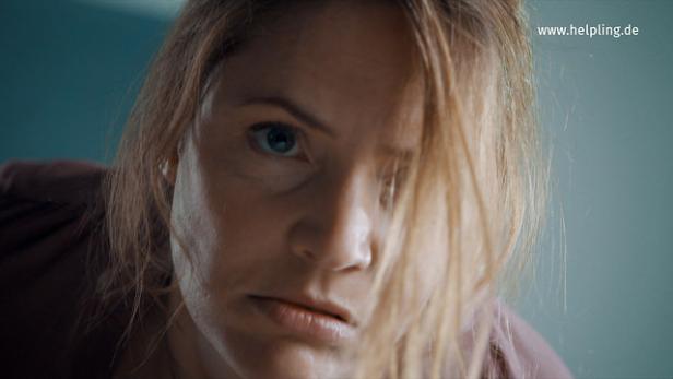 Eine Frau mit blonden Haaren blickt ernst in die Kamera.