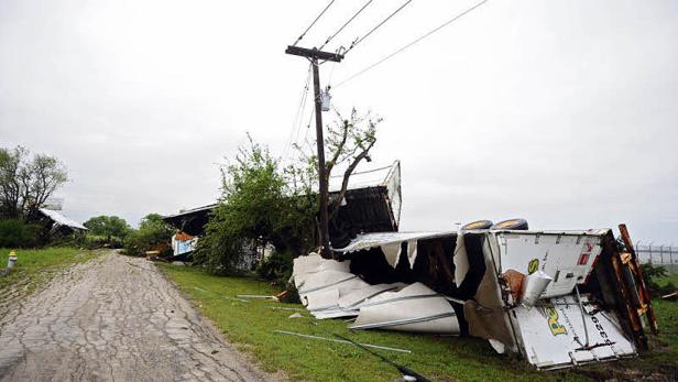 Ein umgestürzter Lastwagen liegt neben einem beschädigten Haus nach einem Sturm.