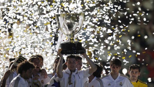 Cristiano Ronaldo hält eine Trophäe inmitten von Konfetti hoch, umgeben von seinen Teamkollegen.