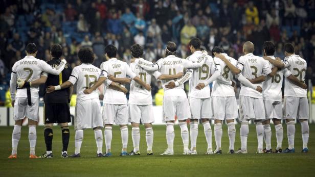 Die Fußballmannschaft von Real Madrid steht mit verschränkten Armen auf dem Spielfeld.