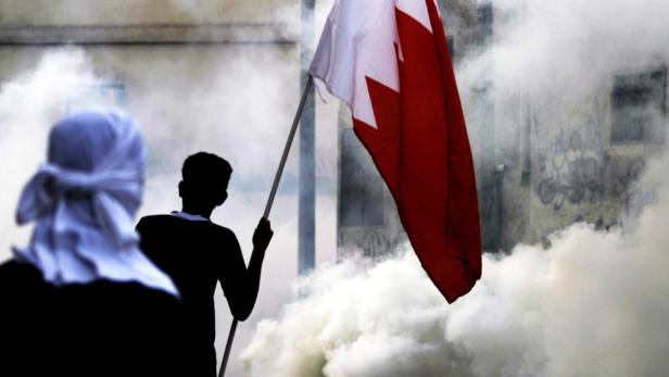 Eine Person hält eine Bahrain-Flagge inmitten von Rauch.