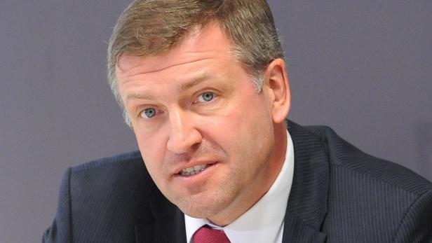 Ein Mann mit hellen Augen und einem dunklen Anzug blickt in die Kamera.