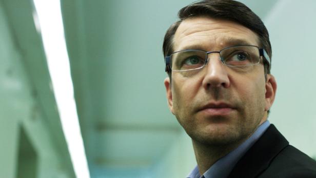 Ein Mann mit Brille und Anzug blickt nach oben.