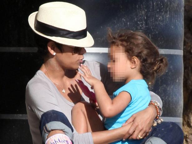 Eine Frau mit Hut hält ein kleines Mädchen im Arm.