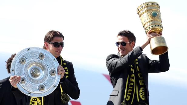 Zwei Fußballspieler von Borussia Dortmund posieren mit der Meisterschale und dem DFB-Pokal.