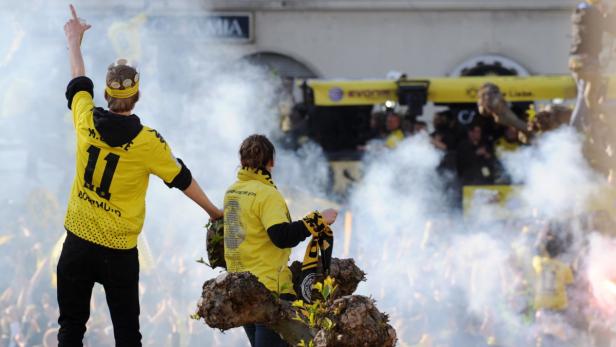 Borussia Dortmund Fans feiern auf einem Wagen mit Rauch und gelben Trikots.