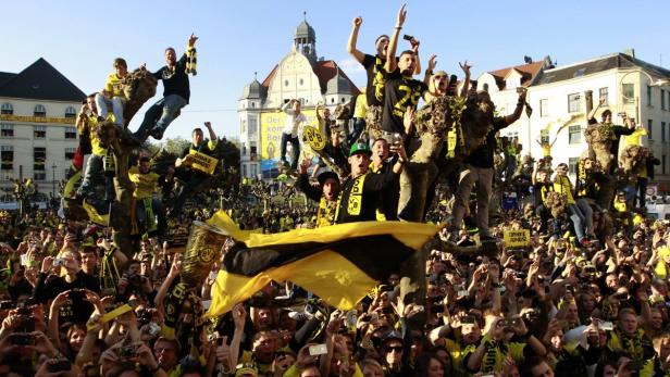 Eine große Menschenmenge, viele in BVB-Trikots, feiert auf einem Platz in Dortmund.