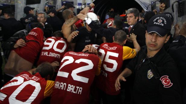 Türkische Polizisten stehen inmitten einer Gruppe von Fußballspielern mit den Nummern 22, 25 und 90 auf ihren Trikots.