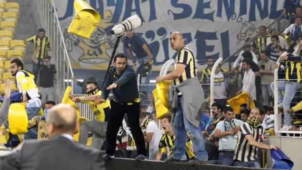 Fans werfen Gegenstände auf das Spielfeld während eines Fußballspiels.