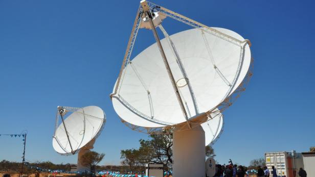 Mehrere große, weiße Radioteleskope stehen unter einem blauen Himmel.
