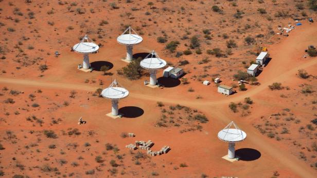 Luftaufnahme von sechs Radioteleskopen in einer wüstenartigen Landschaft.