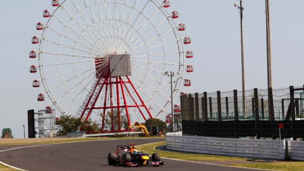 Ein Formel-1-Wagen fährt auf einer Rennstrecke vor einem großen Riesenrad.