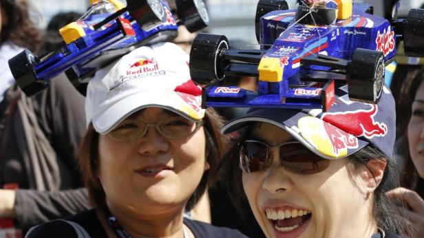 Zwei Frauen mit Red Bull Racing Hüten, auf denen Miniatur-Formel-1-Autos befestigt sind.