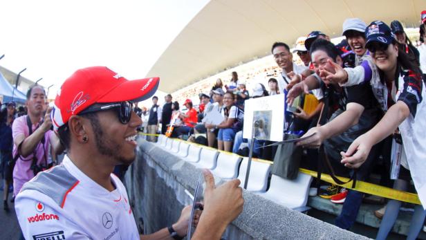 Lewis Hamilton gibt Fans Autogramme.
