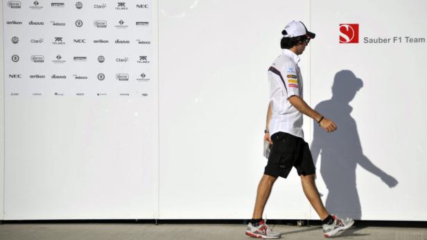 Ein Mann geht vor einer Wand mit dem Sauber F1 Team Logo und Sponsorenlogos entlang.