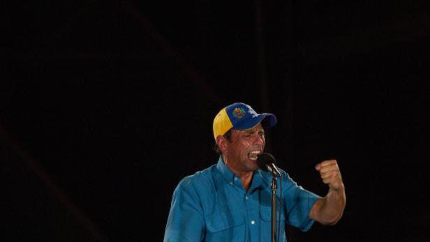 Ein Mann mit Kappe und blauem Hemd spricht in ein Mikrofon und ballt die Faust.