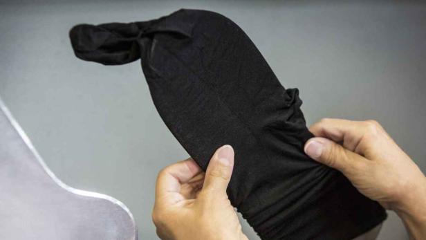 Eine Person hält eine schwarze Sturmhaube in den Händen.