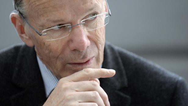 Ein älterer Mann mit Brille denkt nach, den Finger an die Wange gelegt.