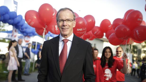 Ein Mann in Anzug und Krawatte steht vor roten und blauen Luftballons der SPÖ.