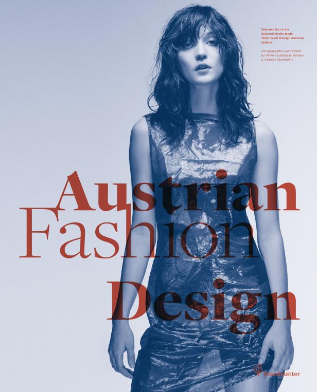 Eine Frau in einem Kleid aus Kunststoff vor dem Hintergrund des Buchcovers „Austrian Fashion Design“.