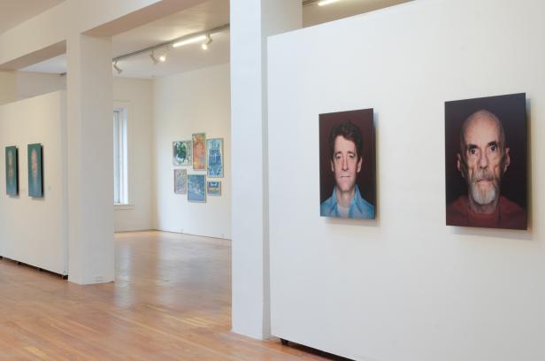 Innenansicht einer Kunstgalerie mit Porträtgemälden an den Wänden.