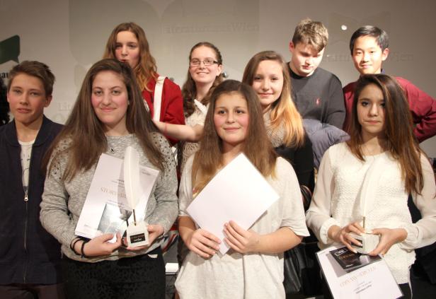 Eine Gruppe Jugendlicher posiert mit Urkunden und Schreibfeder-Trophäen für ein Foto.