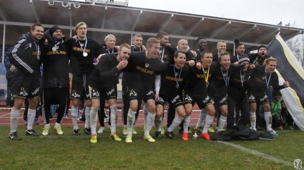 Eine Fußballmannschaft von Seinäjoki feiert mit Medaillen und einem Pokal ihren Sieg.