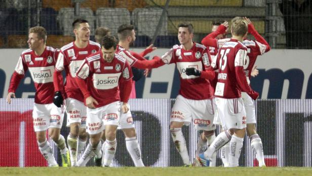 Eine Gruppe Fußballspieler in rot-weißen Trikots feiert auf dem Spielfeld.