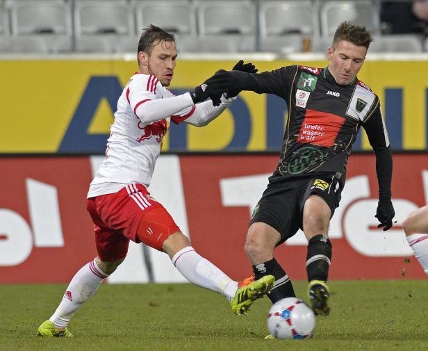 Zwei Fußballspieler kämpfen um den Ball auf dem Spielfeld.