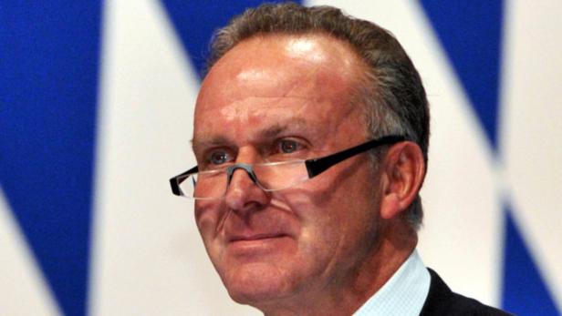 Uli Hoeneß mit Brille vor einem blau-weißen Hintergrund.