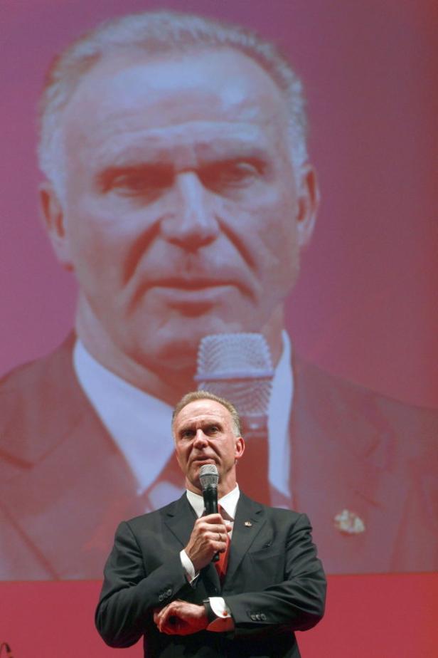 Uli Hoeneß hält eine Rede vor einem großen Porträt von sich selbst.