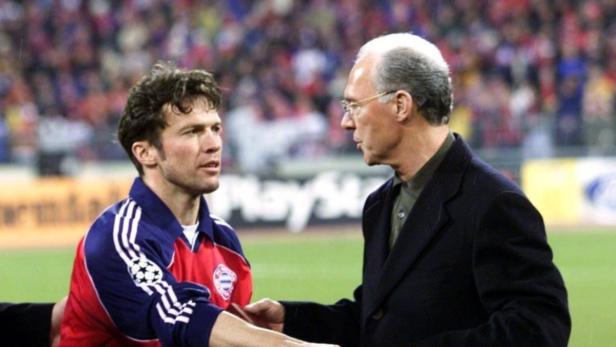 Lothar Matthäus begrüßt Franz Beckenbauer auf dem Fußballfeld.
