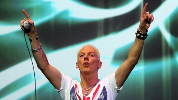 Sänger Scooter alias H.P. Baxxter tritt mit erhobenen Armen auf einer Bühne auf.