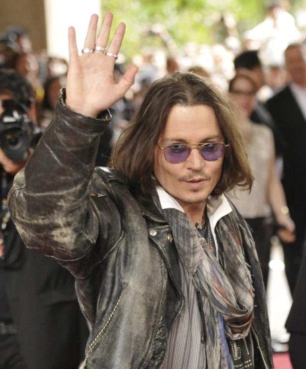 Johnny Depp winkt mit erhobener Hand in die Menge.