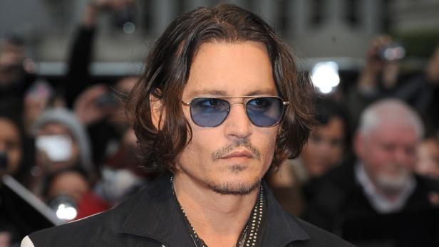 Johnny Depp mit Sonnenbrille posiert vor einer Menschenmenge.