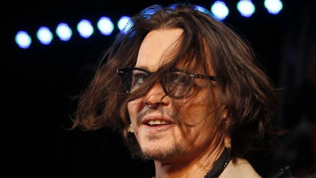 Johnny Depp mit Brille vor dunklem Hintergrund.