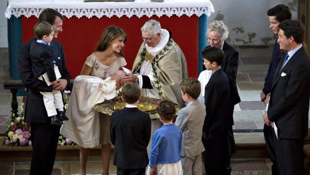 Eine Taufe in einer Kirche mit einer Familie und einem Priester.