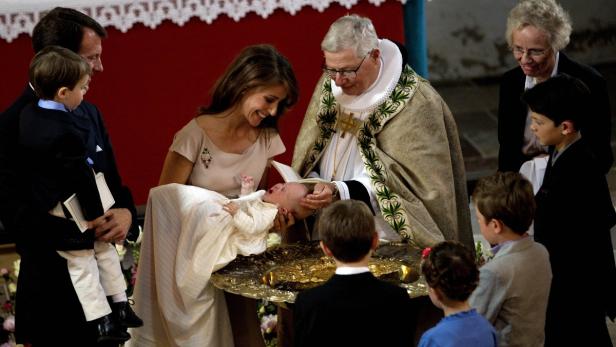Ein Baby wird von einem Priester in Anwesenheit seiner Familie getauft.